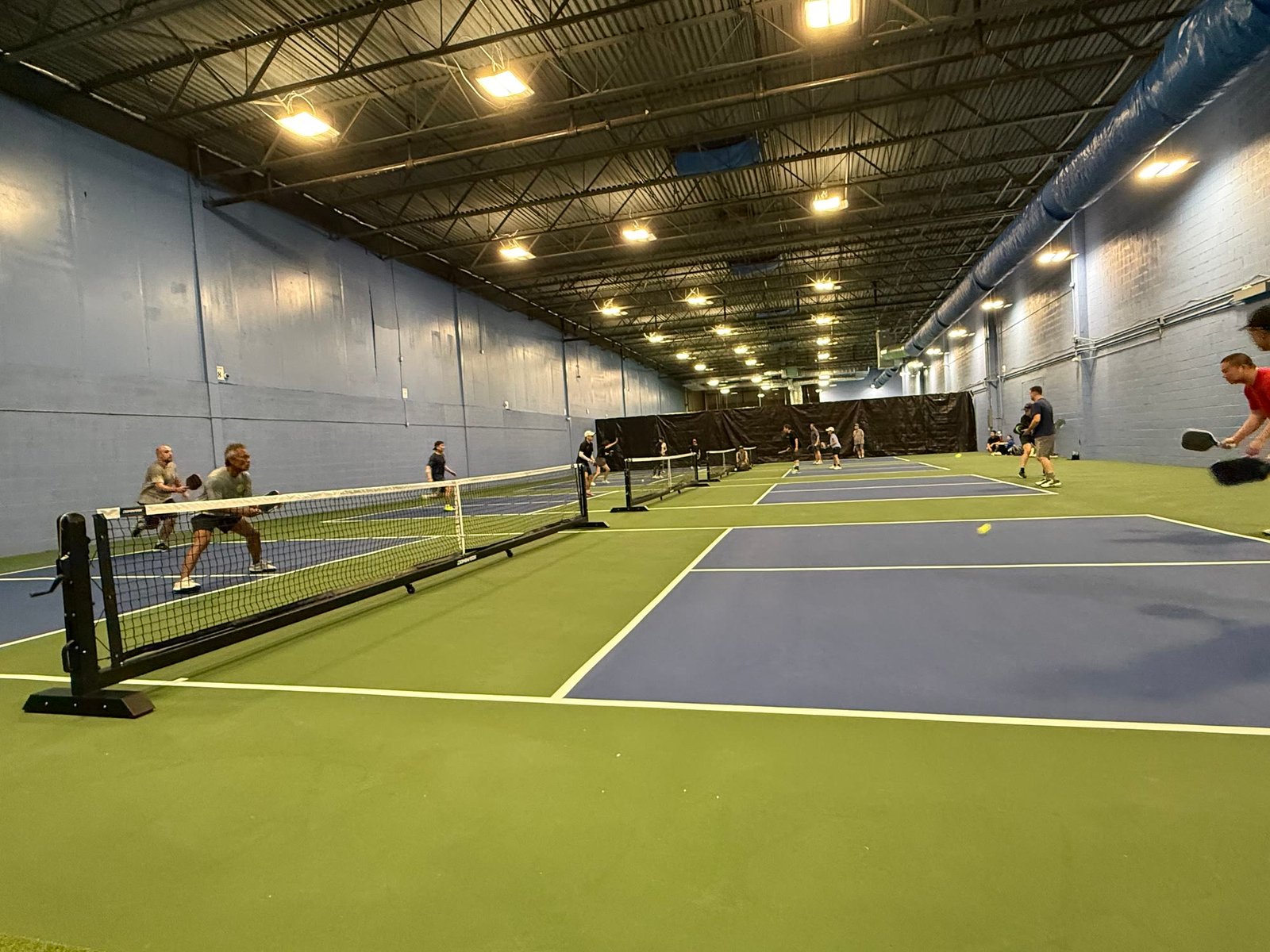 Players rallying across the blue and green indoor courts at All Star