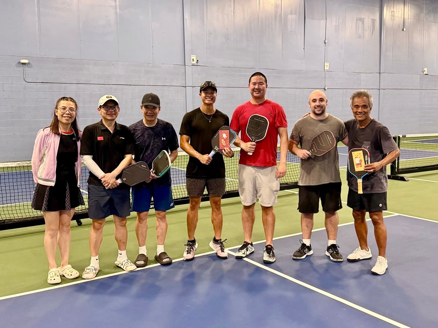 Seven players holding paddles together on court