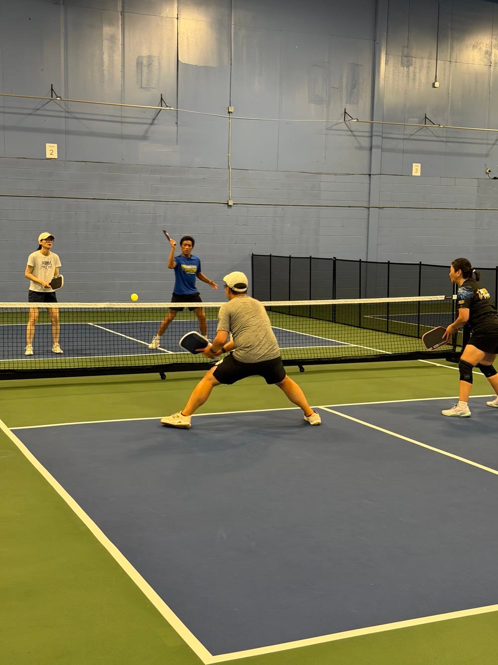 A player lunging for a low ball at the net during doubles